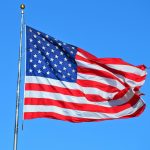 Majestic American flag waving against a bright blue sky, symbolizing freedom and patriotism.